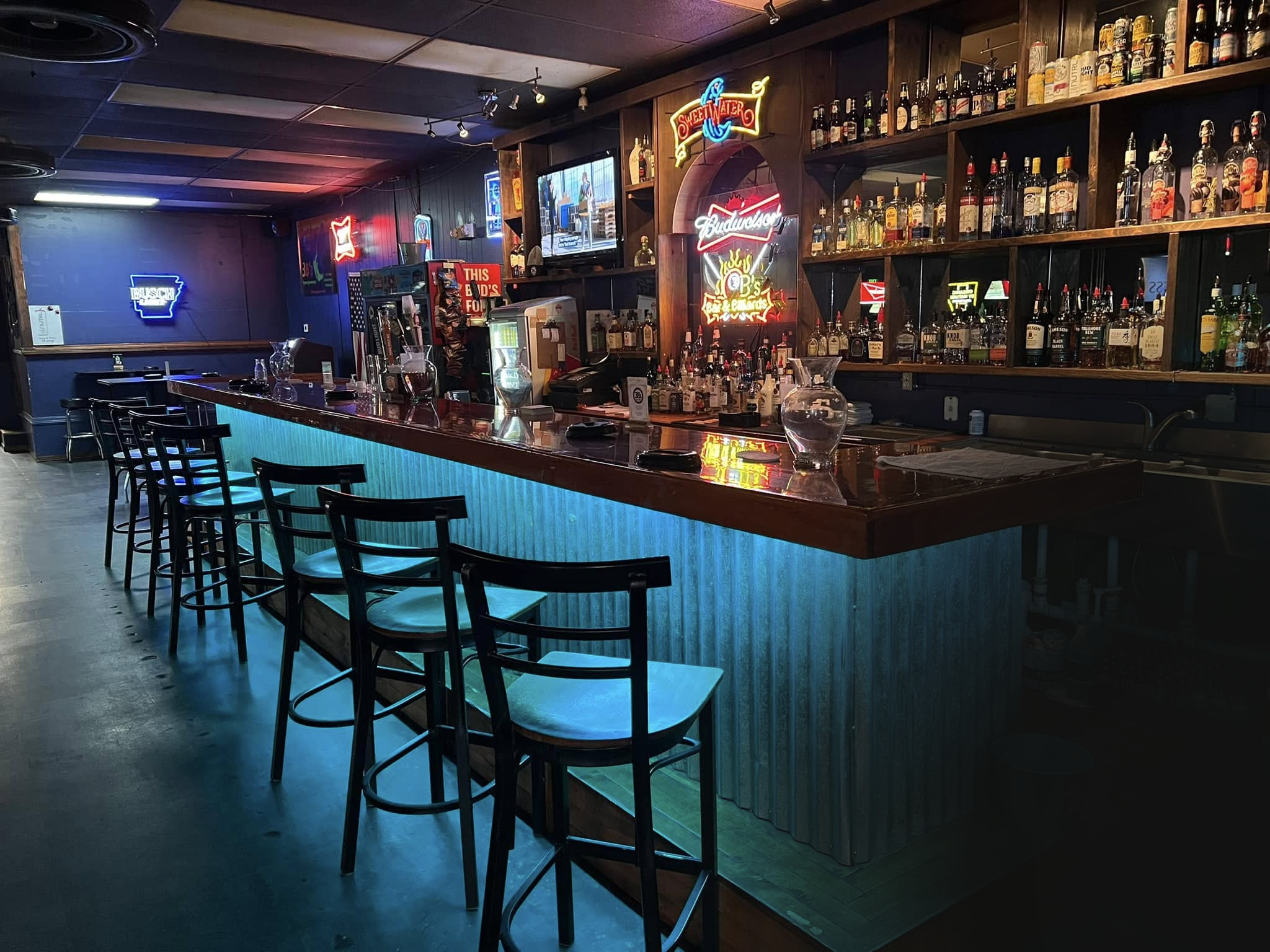 Neon lights glowing above the long wooden bar at 3B’s