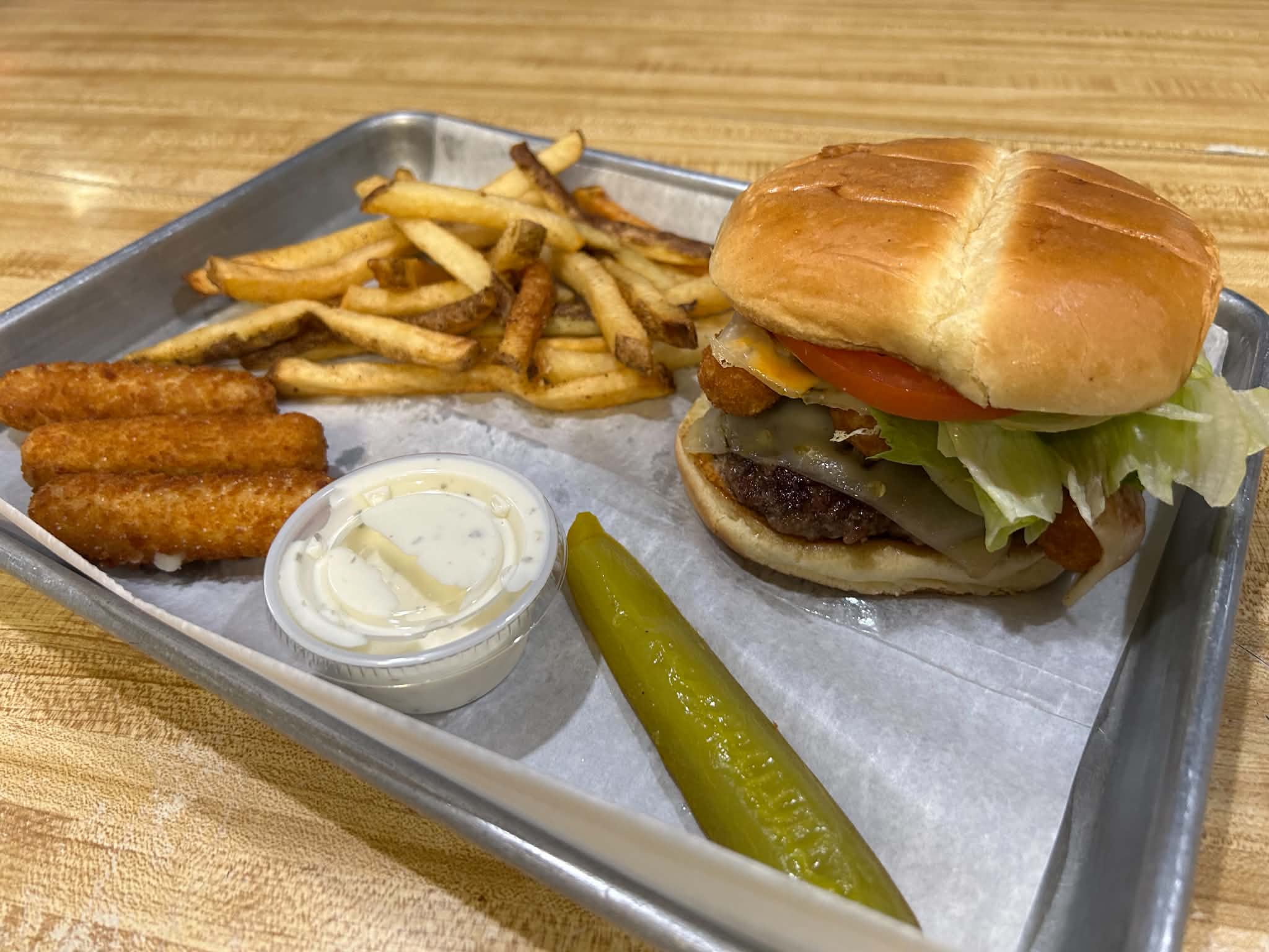 A cheeseburger with fries, mozzarella sticks, ranch, and a pickle