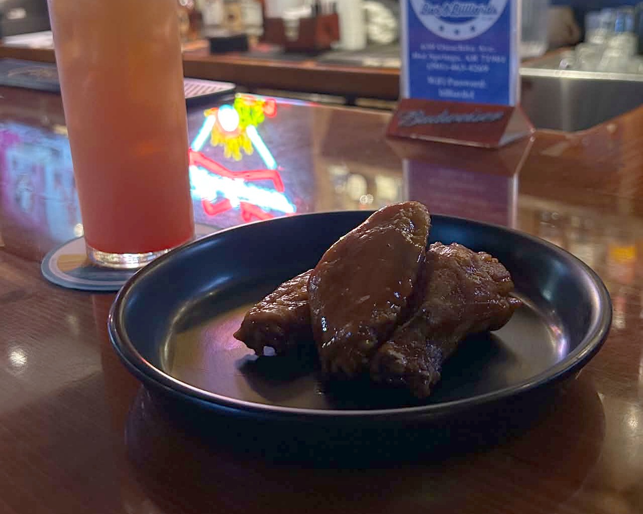 A plate of wings and a drink on the bar at 3B’s